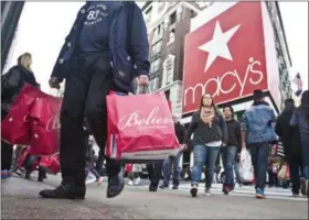  ?? PHOTO COURTESY OF THE ASSOCIATED PRESS ?? Shoppers carry bags as they cross a pedestrian walkway near Macy’s in Herald Square in New York last November.