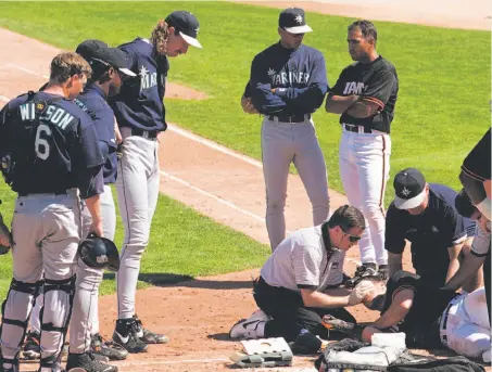  ?? Kevork Djansezian / Associated Press 1997 ?? Giants trainer Mark Letendre tends to J.T. Snow, who was hit in the face by a pitch from Seattle’s Randy Johnson (third from left) in a spring training game in 1997. Snow, beginning his first season with the Giants, hit 28 homers that season, a career...
