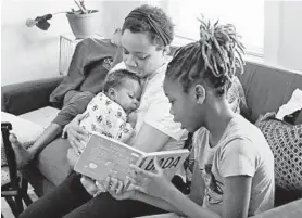  ?? KIM HAIRSTON/BALTIMORE SUN ?? Catina Smith, a personal chef, holds her infant son, Joshua, 2 months, as daughter, Micah, 11, reads to them and son, Isaiah, 12, rests.