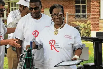  ?? CORNELIUS FROLIK / STAFF ?? Tena Dunson, who acquires and renovates homes to rent out, holds a donated bag of tools and supplies as part of Saturday’s graduation for an electrical program. Dexter McGhee, the instructor and owner of McGhee Electric LLC in Trotwood, helped pass out the certificat­es.