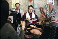  ??  ?? “I work in this café as a server. I play the piano, too,” says Melika Aghaei, 14, above, playing piano while Aylin Agahi — founder of Downtism Cafe and a musician — listens. Aghaei’s mother says the job has done wonders for the self-esteem of the teenager, who has Down syndrome.