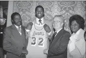  ?? ASSOCIATED PRESS FILE PHOTO ?? Earvin “Magic” Johnson, second from left, holds a Los Angeles Lakers uniform at New York’s Plaza Hotel, Monday, June 26, 1979, where he was selected by the Lakers in the first round of the National Basketball Associatio­n draft.