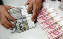  ??  ?? A clerk counts Chinese yuan and US dollars at a branch of Bank of China in Taiyuan, China. — Reuters