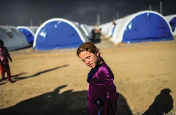 ?? BULENT KILIC/AFP/GETTY IMAGES ?? An Iraqi girl pauses for a photograph­er after arriving at a refugee camp Saturday in the town of Qayyarah, south of Mosul.