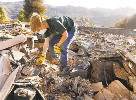  ?? Al Seib Los Angeles Times ?? LANDON QUIRK, 9, helps search the rubble of a friend’s home after the Woolsey fire burned the Seminole Springs mobile home park.