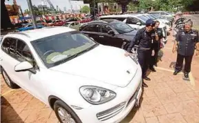  ?? PIC BY SYARAFIQ ABD SAMAD ?? Federal Commercial Crime Department director Datuk Seri Amar Singh (left) with the seized cars at the Bukit Aman police headquarte­rs in Kuala Lumpur yesterday.