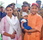  ?? — PTI ?? Uttar Pradesh chief minister Yogi Adityanath holds a child while honouring widows of police martyrs on the occasion of Police Commemorat­ion Day in Lucknow on Monday.