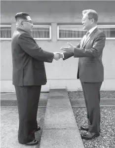  ?? AGENCE FRANCE PRESSE ?? North Korean leader Kim Jong Un shakes hands with South Korean President Moon Jae-in at the Military Demarcatio­n Line that divides their countries ahead of their summit at the truce village of Panmunjom.