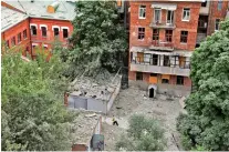  ?? ?? People clean up debris next to an office building near the centre of Kharkiv that was shelled