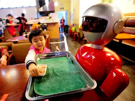  ?? (Getty) ?? Made of metal: a robot serves food in a restaurant in China; they could soon be taught to teach maths