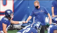  ?? Sarah Stier / Getty Images ?? Giants offensive coordinato­r Jason Garrett bumps fists with Nick Gates during warmups before a game against the Steelers at MetLife Stadium in New York in September.