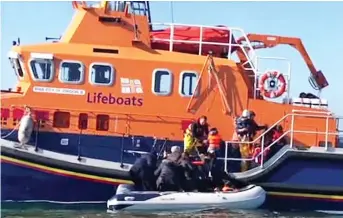  ??  ?? Rescue: Lifeboat crew lift migrants from their dinghy in the Channel yesterday
