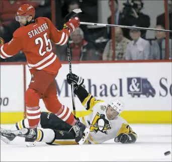  ?? Gerry Broome/Associated Press ?? Patric Hornqvist falls to the ice while chasing the puck with Carolina’s Viktor Stalberg in the first period Tuesday at PNC Arena in Raleigh, N.C.