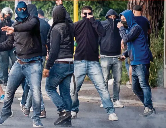  ?? GETTY IMAGES ?? Grim viewing: a group of hooded Lazio supporters clash with riot police after the derby against Roma in 2015