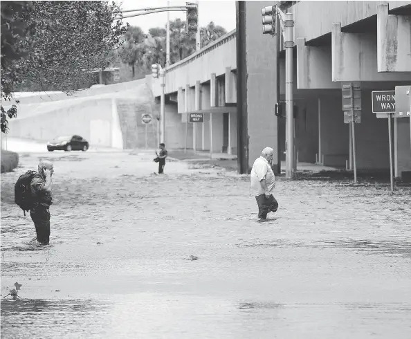  ??  ?? Pedestrian­s make their way through downtown streets after Tropical Storm Irma brought flood waters to Jacksonvil­le, Fla., on Monday. JOHN RAOUX / THE ASSOCIATED PRESS