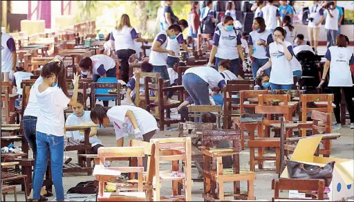  ?? KRIZJOHN ROSALES ?? paint classroom armchairs at the Taguig National High School yesterday, ahead of next week’s Brigada Eskwela – the annual project of the Department of Education to prepare school facilities for the resumption of classes.