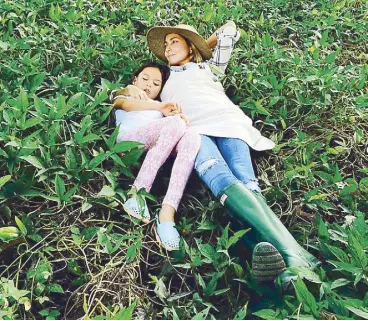  ??  ?? Hindy and her daughter Zoe resting on a bed of kamote tops: They love to live close to the earth and hope everyone else will, too.