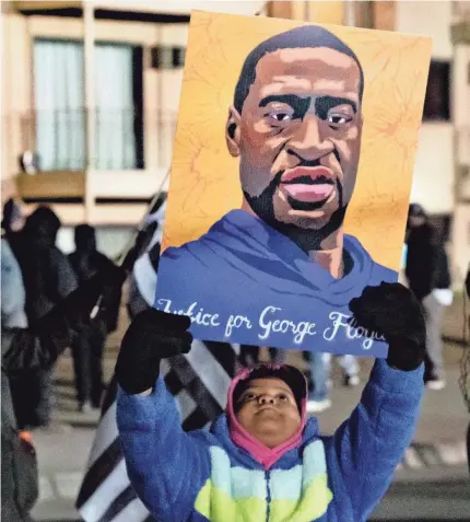  ?? TREVOR HUGHES/USA TODAY NETWORK ?? Zaidia Schwab, 7, holds a picture of George Floyd on Tuesday in Brooklyn Center, Minn.