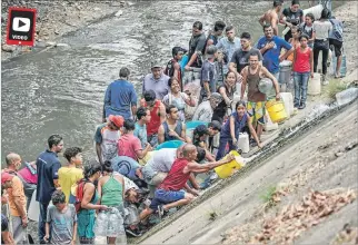  ?? JUAN BARRETO / AFP ?? Escasez. Por la falta de agua, un grupo de venezolano­s la recolectab­an ayer de un canal en Caracas.