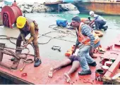  ??  ?? The fishermen on KT05 barge being given first aid by Guo Wang