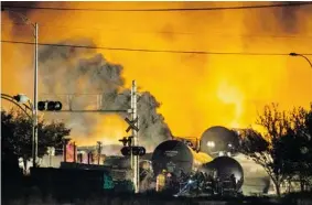  ?? DARIO AYALA/Postmedia News file photo ?? Smoke and fire rises over train cars as firefighte­rs inspect the area after a train carrying
crude oil derailed and exploded in Lac-Megantic, Que., on July 6.