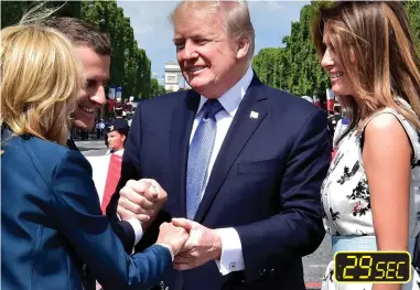  ??  ?? ... but as he grasps her hand, he still refuses to relinquish his iron grip on Mr Macron