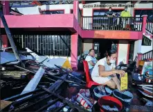  ?? NATHALIA ANGARITA / REUTERS ?? The owner of a supermarke­t washes merchandis­e she could save after the passage of Storm Iota, in Providenci­a, Colombia, on Nov 22.