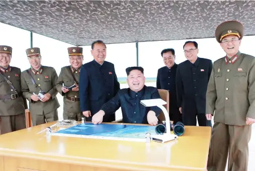  ??  ?? North Korean leader Kim Jong-un, center, smiles as he inspects the test launch of a Hwasong-12 intermedia­te range missile in Pyongyang on Tuesday. (AP)