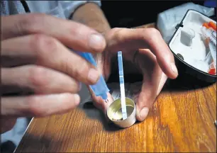  ?? BEBETO MATTHEWS/AP ?? An addict prepares heroin, placing a fentanyl test strip into the mixing container to check for contaminat­ion.