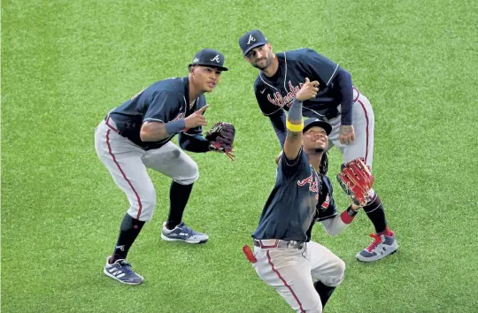  ?? Ron Jenkins, Getty Images ?? Ronald Acuna Jr., front, Cristian Pache, left, and Nick Markakis of the Atlanta Braves celebrate with a pretend selfie after the teams 8- 7 victory over the Los Angeles Dodgers on Tuesday night in Game 2 of the NLCS at Globe Life Field in Arlington, Texas.