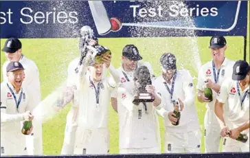  ?? OLI SCARFF/AFP ?? England captain Joe Root (third left) lifts the trophy as his teammates celebrate after winning the fourth Test and the series against South Africa at Old Trafford cricket ground in Manchester on Monday.