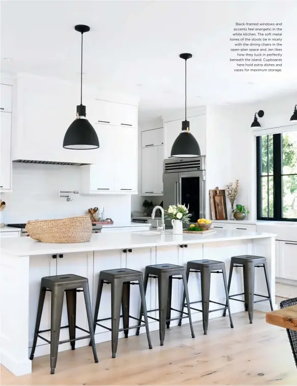  ??  ?? Black-framed windows and accents feel energetic in the white kitchen. The soft metal tones of the stools tie in nicely with the dining chairs in the open-plan space and Jen likes how they tuck in perfectly beneath the island. Cupboards here hold extra dishes and vases for maximum storage.