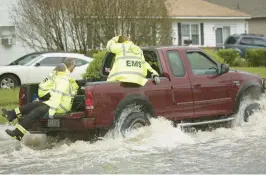  ?? L. TODD SPENCER/STAFF FILE ?? Members of the Virginia Beach Rescue Squad use the back of a raised pickup truck to make a call off of South Plaza Trail in Virginia Beach as Hurricane Matthew moves through Hampton Roads in 2016.