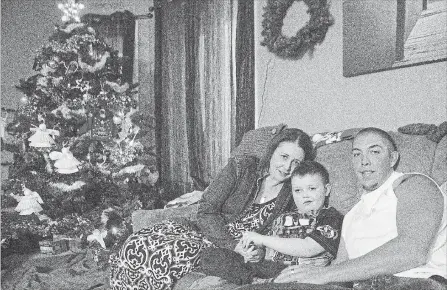  ?? CHRIS YOUNG THE CANADIAN PRESS ?? Evan Leversage, centre, sits in his family home with mother Nicole Wellwood, left, and father Travis Leversage before watching a Christmas Parade in St. George, Ont., on Oct. 24, 2015. The village came together to throw Evan, who was terminally ill...