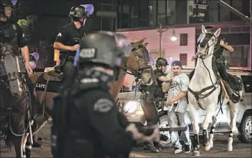  ?? Jason Armond Los Angeles Times ?? POLICE CONFRONT a man as they try to disperse crowds in downtown L. A. early Wednesday. “Right now we are embarrassi­ng ourselves, in a sports celebratio­n, across the world,” LAPD Chief Michel Moore said.