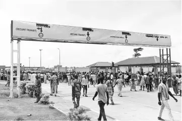  ?? – AFP photo ?? People walk on the main road to the newly built Nigeria-Benin joint border posts on the day of the inaugurati­on at Seme-Krake in Badagry district of Lagos, Nigeria’s commercial capital.The presidents of both countries inaugurate­d the newly built Seme-Krake joint border posts to enhance free movement of people and goods and economic activities in the region.