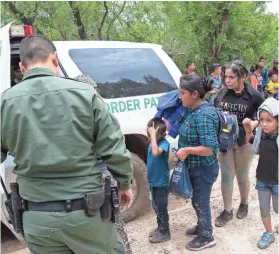  ??  ?? Border Patrol agents take a group of migrant families to a safer place to be transporte­d after intercepti­ng them near McAllen, Texas on Tuesday, June 19. More than 2,300 children have been separated from their parents at the border as a result of the...