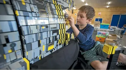  ?? MURRAY WILSON/STUFF ?? Elliott Halman, 7, helps his dad Mike Halman and Brian Cook set up their huge sci-fi themed Lego diorama.