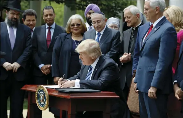  ?? PHOTO ?? In this Thursday photo, President Donald Trump signs an executive order aimed at easing an IRS rule limiting political activity for religious organizati­ons, in the Rose Garden of the White House in Washington. AP