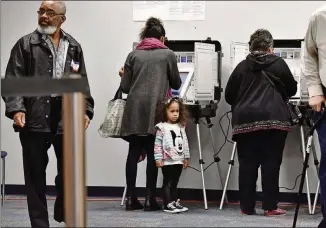  ?? HYOSUB SHIN / HSHIN@AJC.COM ?? Drina Ramos (center) casts her ballot as her 3-year-old daughter Talon, 3, waits during early voting at the Gwinnett County Voter Registrati­ons and Elections Office in Lawrencevi­lle on Oct. 18. One way to foster an interest in voting is to bring your child every time you cast a ballot.