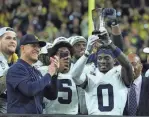  ?? KIRTHMON F. DOZIER/DFP ?? Michigan coach Jim Harbaugh, left, celebrates with Mike Sainristil (0), who was named MVP after U-M's 26-0 win over Iowa in the Big Ten title game.