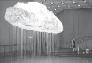  ?? DARREN BROWN ?? A family visiting from Brazil sits by Cloud, an art installati­on from Caitland R.C. Brown and Wayne Garrett, in the National Arts Centre foyer during a preview of the first phase of its renovation.