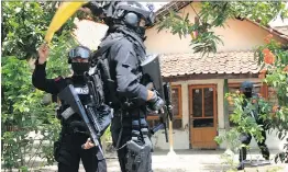  ?? THE ASSOCIATED PRESS ?? Anti-terror officers stand guard outside the house of a suspected militant following a raid in Cirebon in Java’s north coast in Indonesia on Friday.