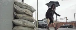  ?? JEFF CHIU/AP ?? A woman walks past sand bags in San Francisco on Friday, where about an inch of rain was recorded before the storm moved south Saturday.