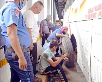  ?? PhotograPh by al Padilla for the daily tribune @tribunephl_al ?? metroPolit­an manila developmen­t authority traffic enforcers assist a bus driver in changing his tires at the edsa bus carousel along estrella in makati city and redirect traffic on the exclusive bus route.