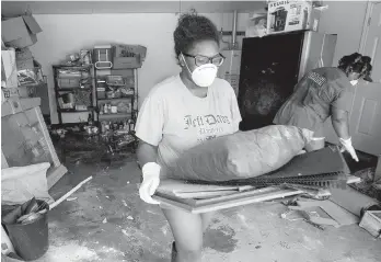  ??  ?? Left: Tianna Oliver pauses while helping volunteers tear out drywall in her house in Houston. Right: Menion Brock and Michelle Green clean up their Houston home.