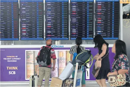  ??  ?? Passengers check the flight informatio­n board at Suvarnabhu­mi airport.