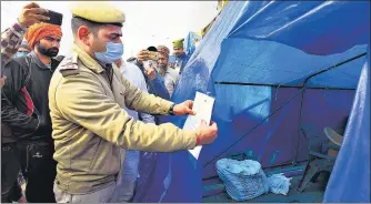  ?? RAJ K RAJ/HT ?? A policeman puts up a notice outside the tent of Rakesh Tikait and Jagtar Singh Bajwa at Ghazipur border on Thursday.