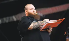  ?? Zachary Mazur / FilmMagic ?? Action Bronson, shown onstage at a music festival with a copy of his new cookbook, has traveled the world for his TV show on Viceland.