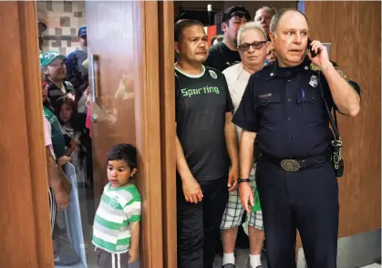  ?? James Tensuan / The Chronicle ?? Deputy Fire Marshal Craig Anderson keeps an eye on a meeting Tuesday in Santa Clara City Council chambers that was packed with youngsters and parents concerned about potentiall­y losing youth soccer fields to the 49ers.